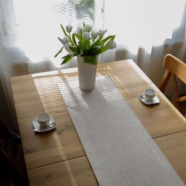 Drinking coffee together on a table set with cork leather products, table runner in striped light finish